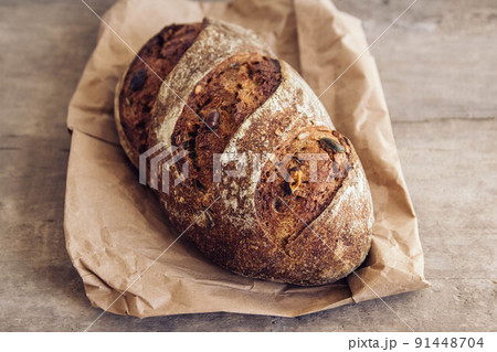 Brown fresh bread with seeds on old wood background. Top view, copy space Brown fresh bread with seeds on old wood background. Top view, copy space 91448704