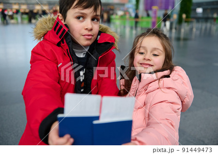 Adorable kids siblings hold boarding pass and Identity document in hands while waiting for check-in flight in departure hall of international airport 91449473