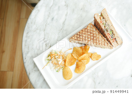 Tuna sandwich and chips on a plate on table , Tuna sandwich and chips on a plate on table , 91449941