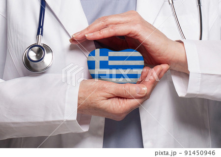 Greek doctor holding heart with flag of Greece background. Healthcare, charity 91450946