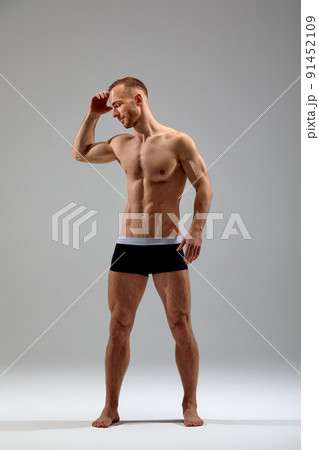 Young male athlete posing. Handsome athletic male power guy. Fitness muscular person. Young athlete showing muscles in the studio, posing shirtless on gray background. Young male athlete posing. Handsome athletic male power guy. Fitness muscular person. Young athlete showing muscles in the studio, posing shirtless on gray background. 91452109
