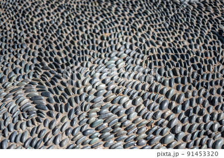 Selective focus on decorative pattern of river rocks laid in garden footpath.  91453320