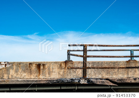 Damaged and bent guardrail along the edge of a bridge that needs repaired. 91453370
