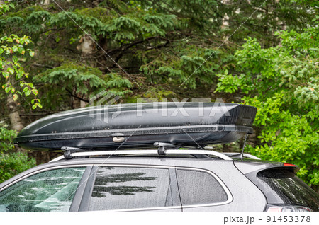 Roof rack and cargo box mounted on a vehicle with active precipitation. 91453378