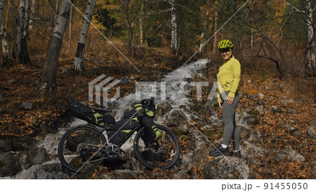 The woman travel on mixed terrain cycle touring with bikepacking. The traveler journey with bicycle bags. Sport tourism bikepacking. The woman travel on mixed terrain cycle touring with bikepacking. The traveler journey with bicycle bags. Sport tourism bikepacking. 91455050
