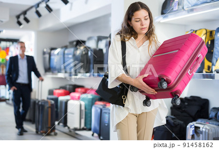 Young girl examines a travel suitcase in a store Young girl examines a travel suitcase in a store 91458162