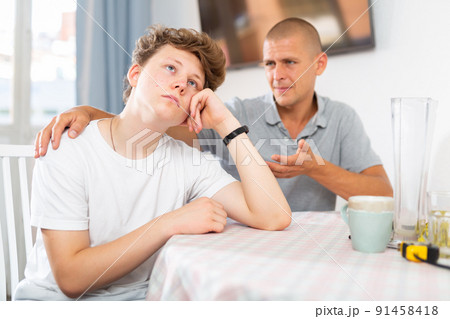 Son feeling sad and father talking to him 91458418