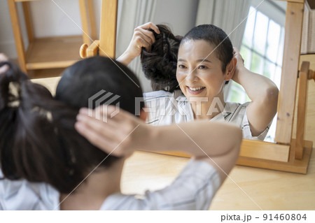 鏡に向かってウイッグをつけるミドルの女性 鏡に向かってウイッグをつけるミドルの女性 91460804