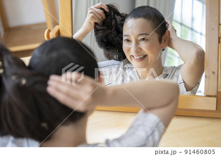 鏡に向かってウイッグをつけるミドルの女性 91460805