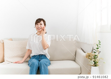 ソファで肌を触ってスキンケアする日本人女性（美容・ハリ・弾力） 91461082