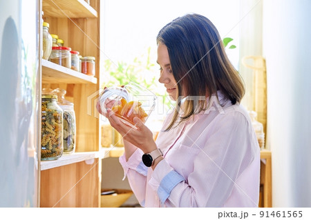 Young woman in kitchen with containers jars of food, with dried apricots 91461565