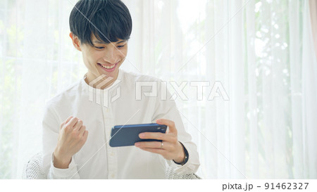 スマホを見て興奮する男性 91462327