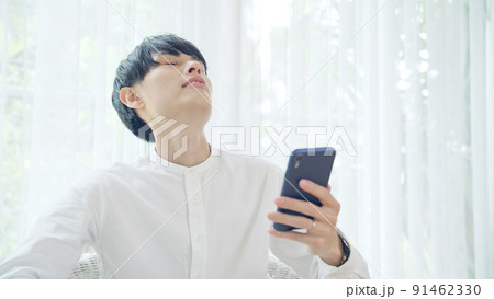 スマホを見ながら悩む男性 91462330