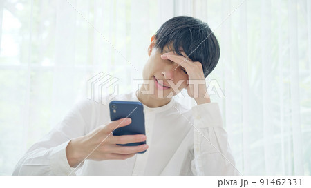 スマホを見ながら悩む男性 91462331