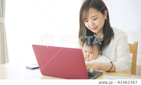 赤ちゃんを抱っこしながら自宅で仕事する女性　子育てしながらの在宅勤務 91462367