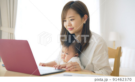 赤ちゃんを抱っこしながら自宅で仕事する女性　子育てしながらの在宅勤務 91462370