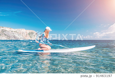Healthy happy fit woman in bikini relaxing on a sup surfboard, floating on the clear turquoise sea water. Recreational Sports. Stand Up Paddle boarding. Summer fun, holidays travel. Active lifestyle 91463197