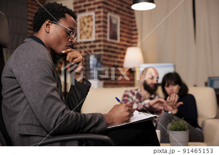 Frustrated therapist taking notes on paper at couple therapy session with married partners, having relationship conflict and difficulties. Trying to solve problems with psychology advice. 91465153