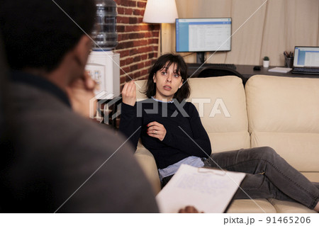 Unhappy woman laying on sofa at psychotherapy session with therapist, talking about stress and problems. Receiving support and help from professional counselor, behavior guidance. 91465206