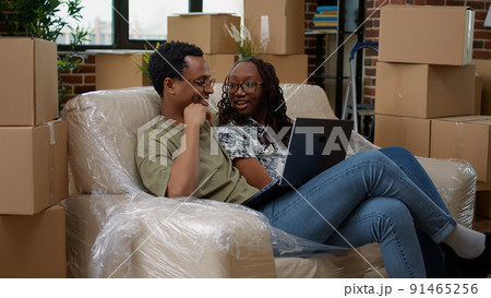 Husband and wife doing online shopping for home decor, finding inspiration to place furniture and move into new apartment. Buying decoration on website, moving in flat bought on loan. 91465256
