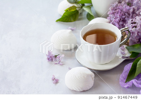Delicate vanilla marshmallow on a white delicate plate. Still life with marshmallows, a cup of tea and lilac lilac against a vintage stone background. Copy space. Delicate vanilla marshmallow on a white delicate plate. Still life with marshmallows, a cup of tea and lilac lilac against a vintage stone background. Copy space. 91467449