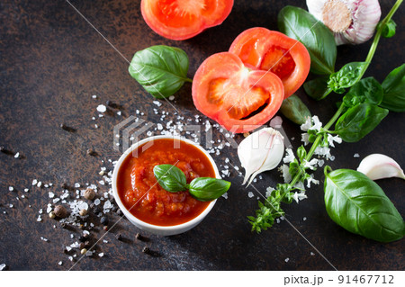 Tomato ketchup sauce in a bowl with spices, basil leaves and tomatoes on the kitchen table. Tomato ketchup sauce in a bowl with spices, basil leaves and tomatoes on the kitchen table. 91467712