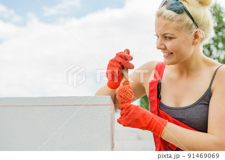 Woman using string as level in wall construction. Woman using string as level in wall construction. 91469069
