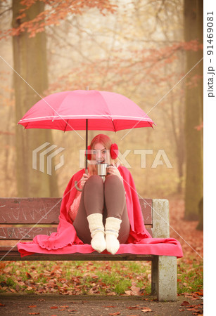 Girl in autumn park enjoying hot drink Girl in autumn park enjoying hot drink 91469081