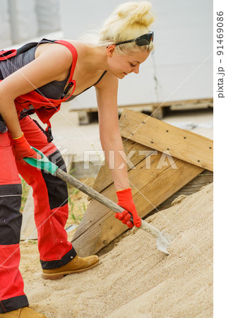 Woman using shovel on constriction site Woman using shovel on constriction site 91469086