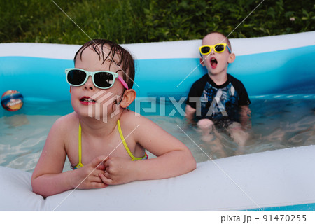 Wet serious children in the pool in sunglasses. Summer is a time of pleasure and fun 91470255