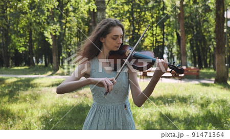 A young girl plays the violin in the city park. | materials | digitalstage