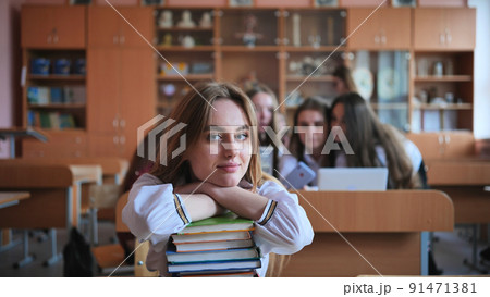 A student poses with textbooks at her desk in her class. 91471381