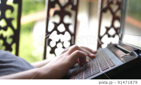 Freelancer works remotely by notebook, lying in hammock in a tropical garden 91471879