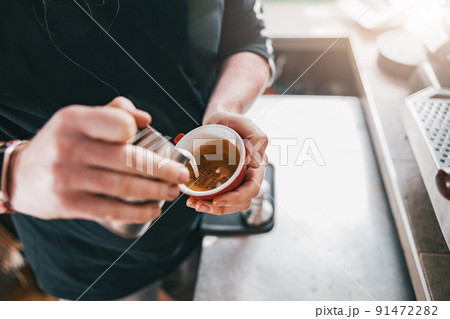 Professional Barista pouring milk in cup of fresh made coffee for making latte or cappuccino Professional Barista pouring milk in cup of fresh made coffee for making latte or cappuccino 91472282
