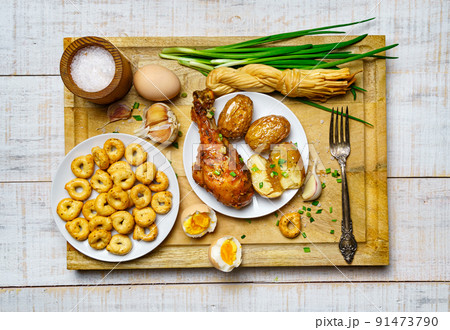 tasty lunch in rural style, healthy food - glass of beer, fried chicken meat and unpeeled potatoes, eggs, green leek, salt and garlic, cooked food on a white wooden boards tasty lunch in rural style, healthy food - glass of beer, fried chicken meat and unpeeled potatoes, eggs, green leek, salt and garlic, cooked food on a white wooden boards 91473790