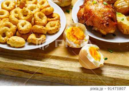 tasty and healthy food, lunch in rural style - fried chicken meat and unpeeled potatoes, eggs, green leek, salt and garlic, cooked food on a wooden kitchen board 91473807