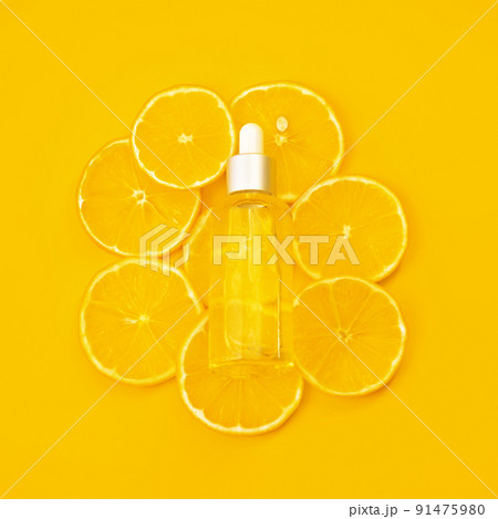 Vitamin C formula ampoule. Serum in transparent bottle with lemons on bright yellow background. Beauty and health concept. Mockup for your design with copy space. Flat lay style. 91475980