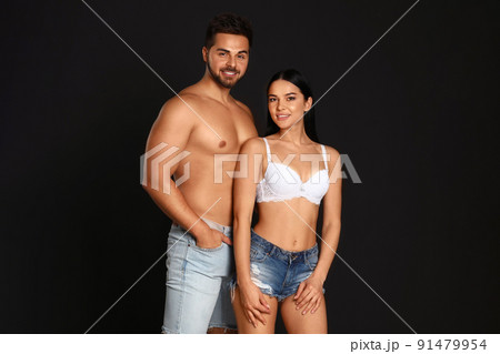 Young woman in underwear and denim shorts with her boyfriend on black background 91479954