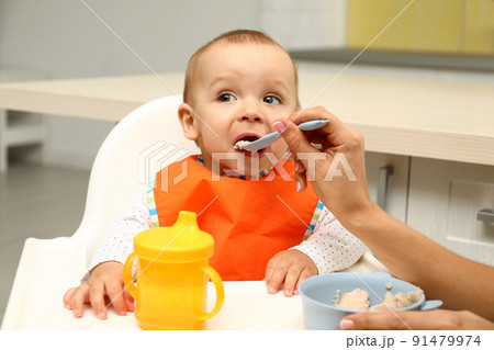Young mother feeding her little baby at home Young mother feeding her little baby at home 91479974