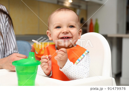 Young mother feeding her little baby at home Young mother feeding her little baby at home 91479976