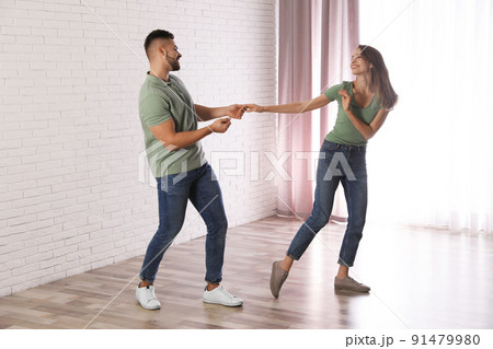 Lovely young couple dancing together at home Lovely young couple dancing together at home 91479980