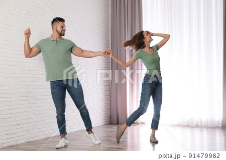 Lovely young couple dancing together at home Lovely young couple dancing together at home 91479982