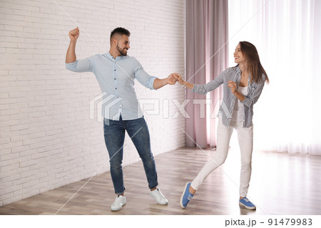 Lovely young couple dancing together at home Lovely young couple dancing together at home 91479983