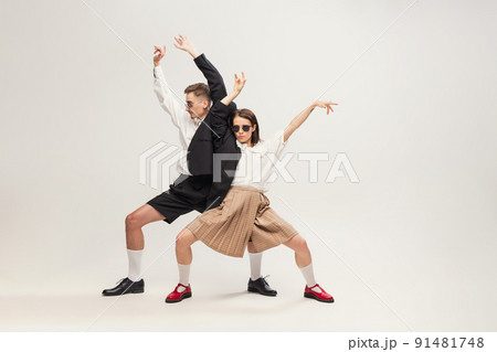 Full-length portrait of stylish young couple, man and woman in retro suit posing isolated over grey studio background. Connected vibe. 91481748