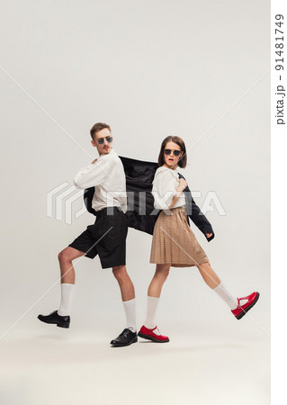 Full-length portrait of stylish young couple, man and woman in retro suit posing isolated over grey studio background Full-length portrait of stylish young couple, man and woman in retro suit posing isolated over grey studio background 91481749