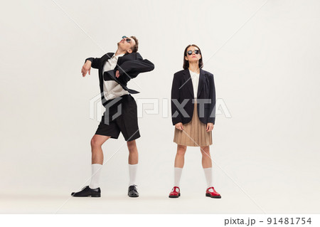 Full-length portrait of stylish young couple, man and woman in retro suit posing isolated over grey studio background. Weird dance Full-length portrait of stylish young couple, man and woman in retro suit posing isolated over grey studio background. Weird dance 91481754