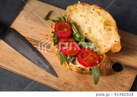 Croissant with sauce and arugula and tomato 91482028