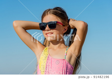 A cheerful girl in a bathing suit holds her hair with her hands. A cheerful girl in a bathing suit holds her hair with her hands. 91482196