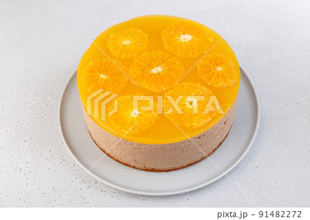 Chocolate-orange mousse cake with biscuit base, jelly and orange circles. Whole homemade cheesecake. Traditional holiday dessert. Selective focus, close-up. Chocolate-orange mousse cake with biscuit base, jelly and orange circles. Whole homemade cheesecake. Traditional holiday dessert. Selective focus, close-up. 91482272