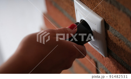 Closeup of hand inserting black plug into white socket 91482531